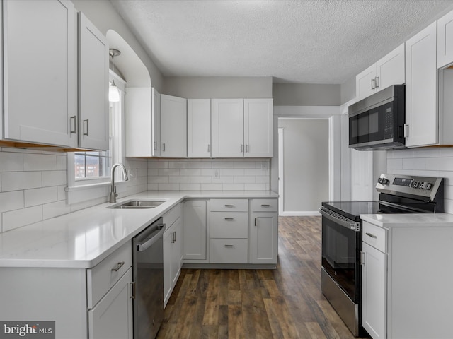 kitchen featuring dark hardwood / wood-style flooring, sink, white cabinets, a textured ceiling, and stainless steel appliances