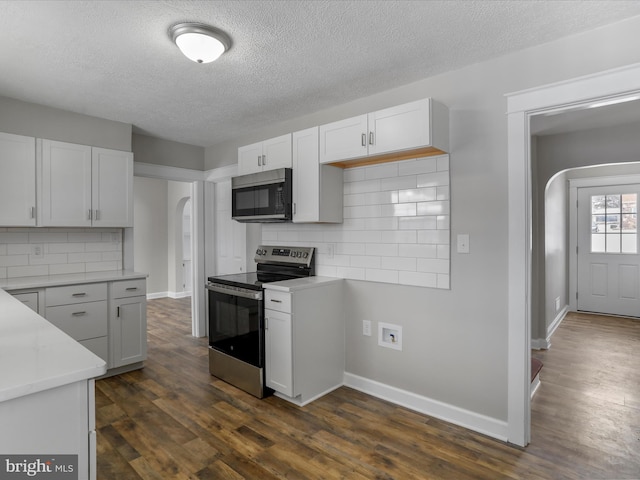 kitchen with backsplash, white cabinetry, appliances with stainless steel finishes, and dark wood-type flooring