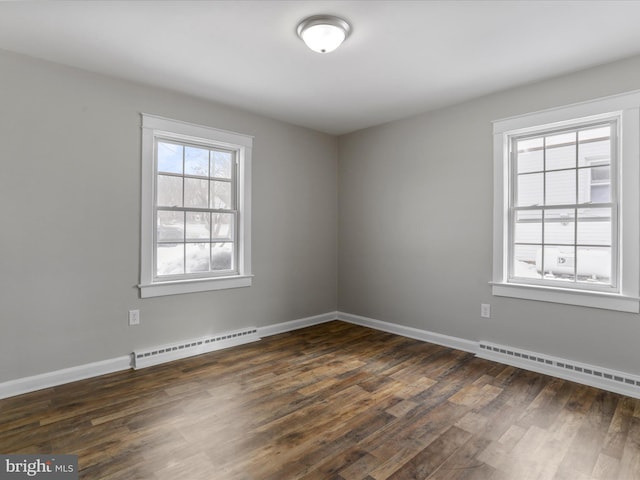 empty room featuring a baseboard heating unit and dark hardwood / wood-style floors