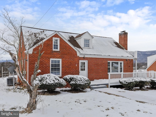 snow covered house featuring central AC unit