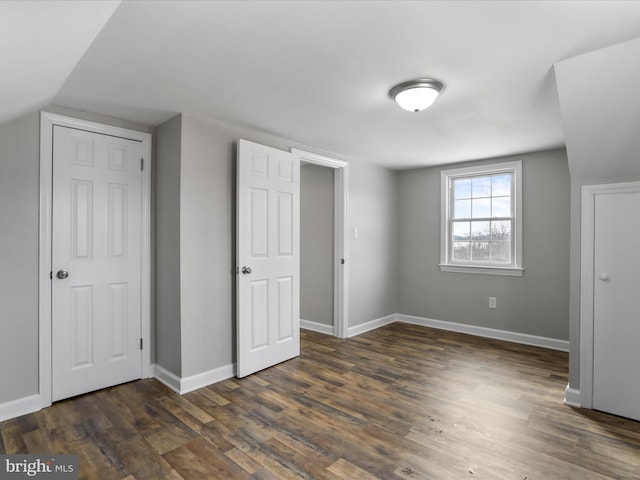 bonus room with dark wood-type flooring and vaulted ceiling