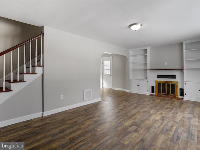 unfurnished living room with dark wood-type flooring and a fireplace