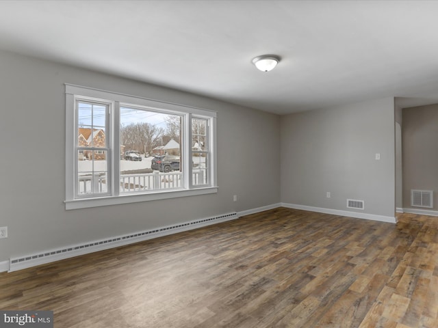 empty room with baseboard heating and dark hardwood / wood-style floors