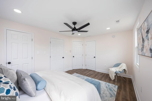 bedroom with ceiling fan, dark hardwood / wood-style floors, and two closets