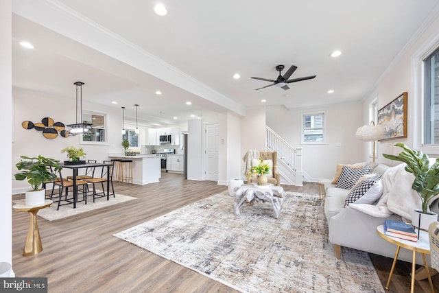 living room featuring crown molding, light hardwood / wood-style flooring, and ceiling fan