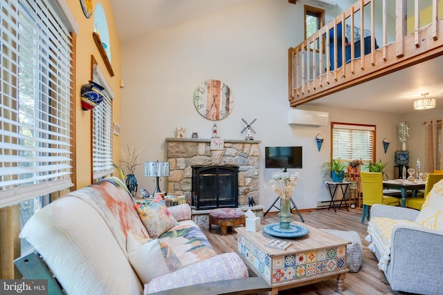 living room featuring a wall mounted air conditioner, wood-type flooring, a fireplace, and a baseboard heating unit