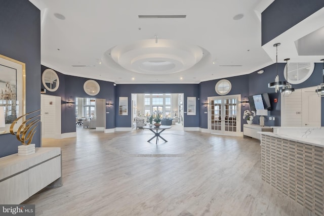 interior space featuring a tray ceiling, french doors, and light hardwood / wood-style floors