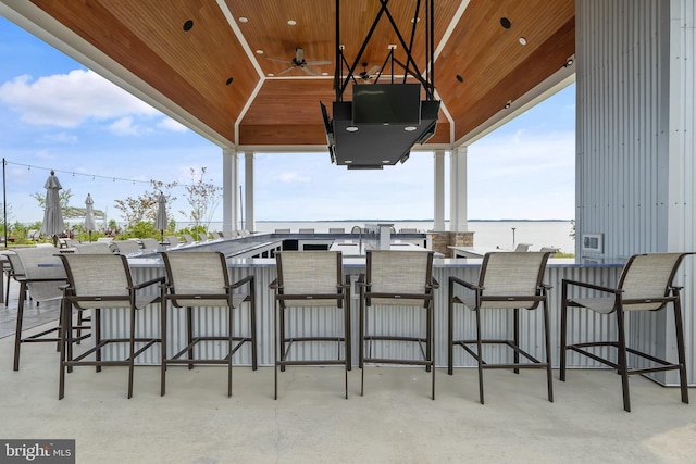 view of patio with ceiling fan and a bar