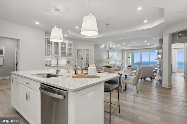 kitchen featuring white cabinetry, sink, a raised ceiling, stainless steel dishwasher, and a center island with sink