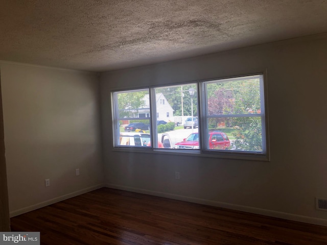 unfurnished room with dark hardwood / wood-style flooring and a textured ceiling