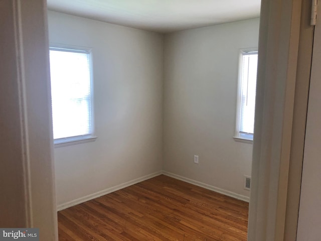 spare room featuring dark wood-type flooring and a wealth of natural light