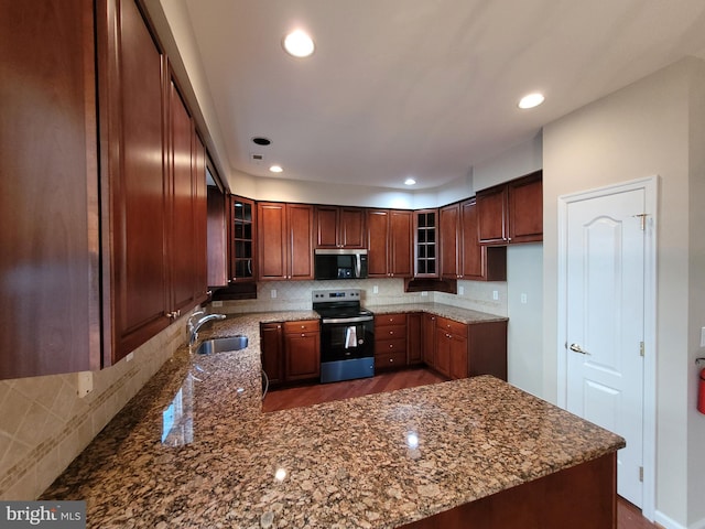 kitchen featuring sink, appliances with stainless steel finishes, tasteful backsplash, stone countertops, and kitchen peninsula