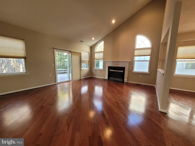 unfurnished living room with dark wood-type flooring and high vaulted ceiling