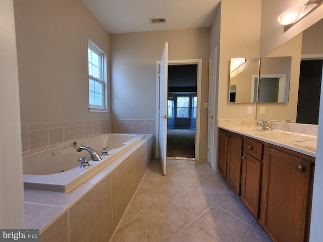 bathroom with tile patterned flooring, vanity, and a relaxing tiled tub