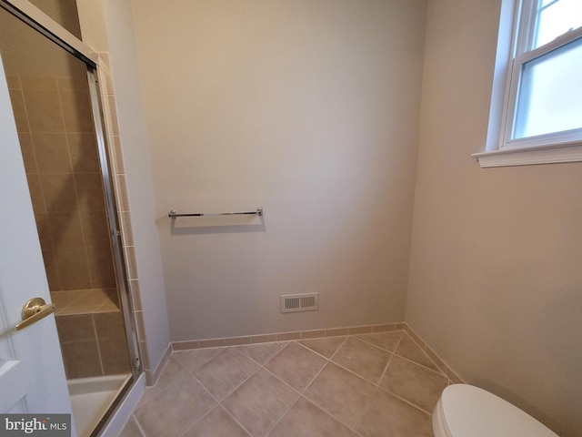 bathroom featuring tile patterned flooring, toilet, and walk in shower