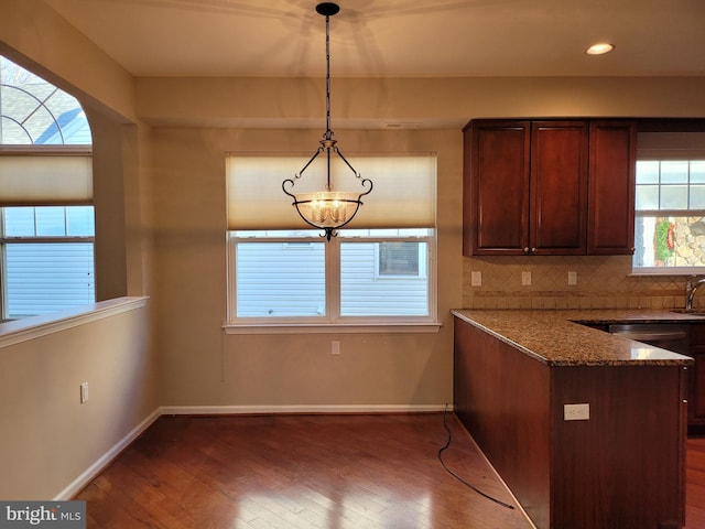 kitchen featuring decorative light fixtures, dark stone countertops, a wealth of natural light, and tasteful backsplash