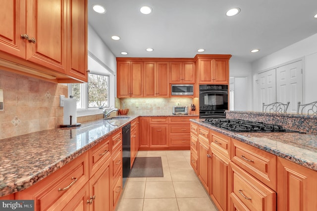 kitchen with black appliances, light stone countertops, backsplash, and light tile patterned floors