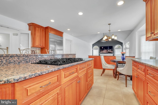 kitchen with stainless steel built in refrigerator, a notable chandelier, black gas stovetop, pendant lighting, and lofted ceiling