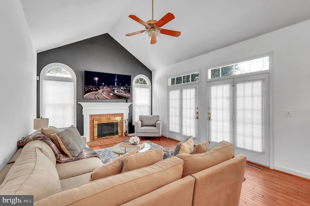 living room with a fireplace, light hardwood / wood-style floors, ceiling fan, and lofted ceiling