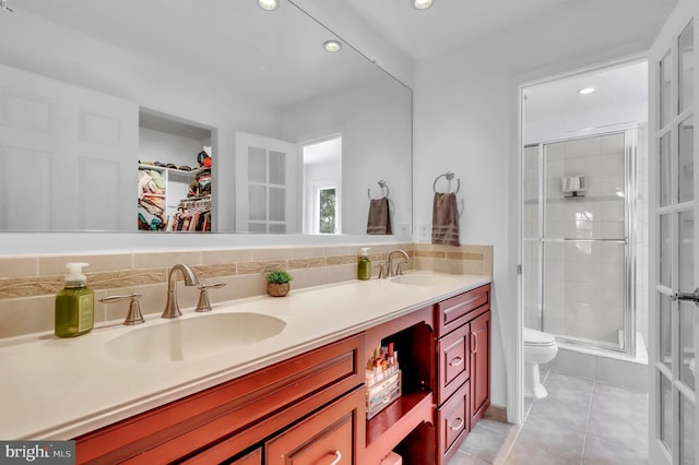 bathroom with tasteful backsplash, tile patterned floors, vanity, a shower with door, and toilet