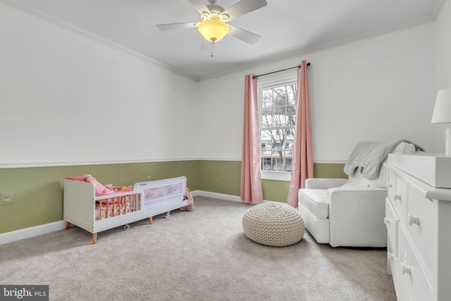 carpeted bedroom featuring ceiling fan, a crib, and ornamental molding