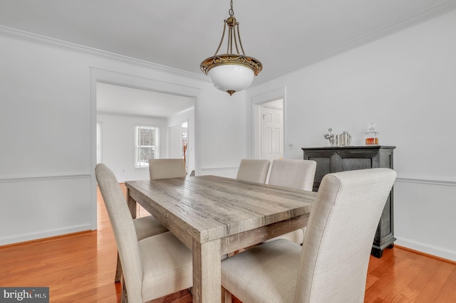 dining space with ornamental molding and light wood-type flooring