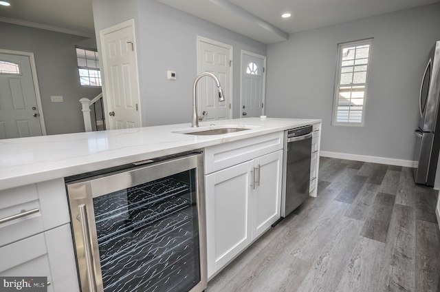 kitchen with white cabinetry, sink, stainless steel appliances, wine cooler, and light hardwood / wood-style flooring