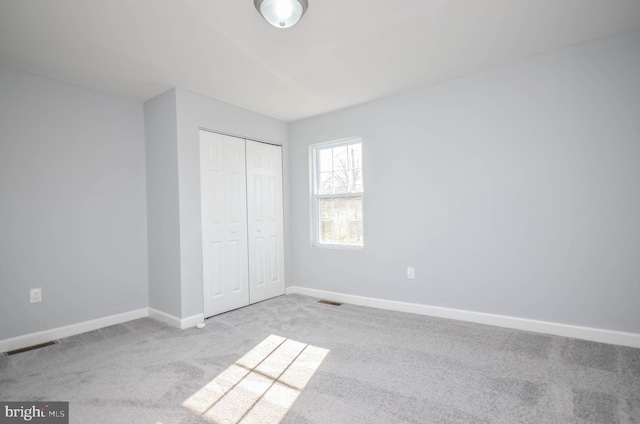 unfurnished bedroom featuring light carpet and a closet