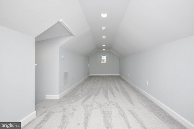 additional living space with light colored carpet and vaulted ceiling