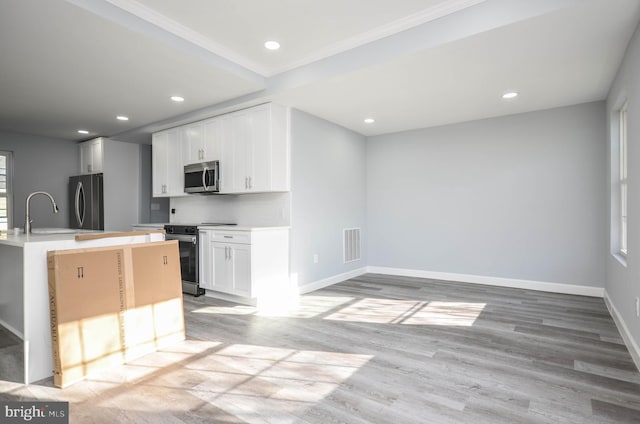 kitchen with sink, light wood-type flooring, ornamental molding, white cabinetry, and stainless steel appliances