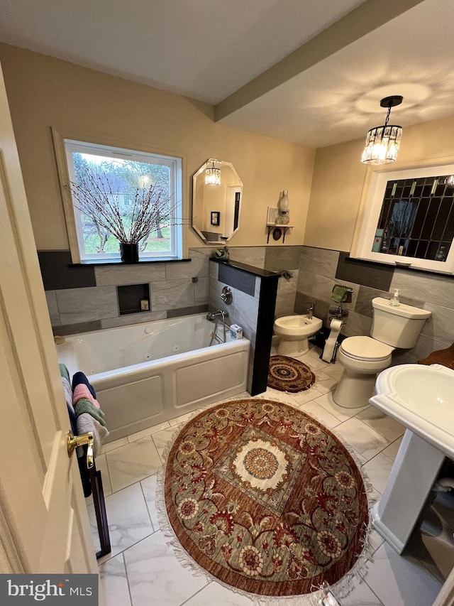 bathroom with a bathtub, toilet, tile walls, and a bidet