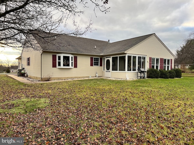 rear view of property with a sunroom and a lawn