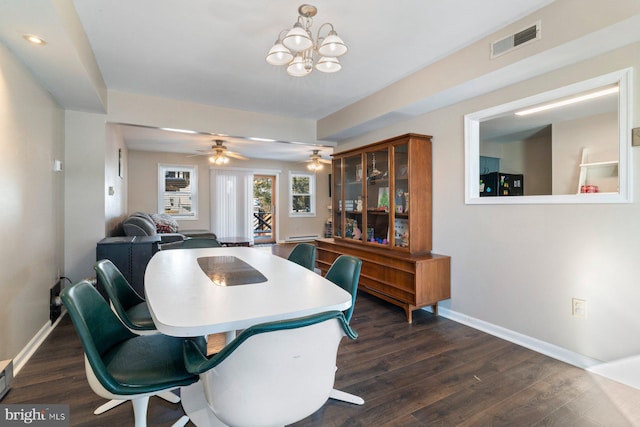 dining space with ceiling fan with notable chandelier and dark hardwood / wood-style flooring