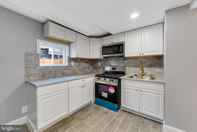 kitchen featuring white cabinets, appliances with stainless steel finishes, decorative backsplash, and sink