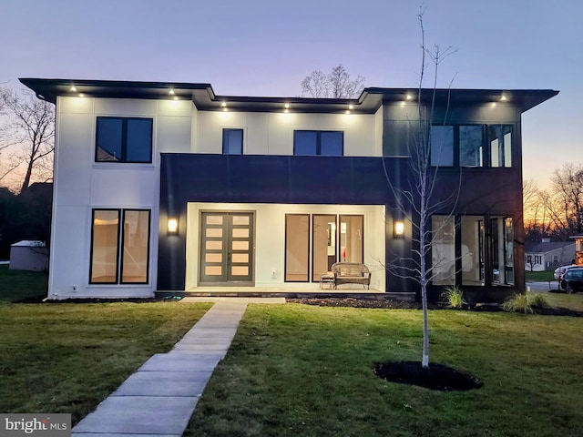 back of house featuring a lawn and stucco siding