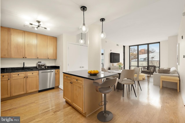 kitchen featuring decorative light fixtures, dishwasher, sink, a kitchen breakfast bar, and light wood-type flooring