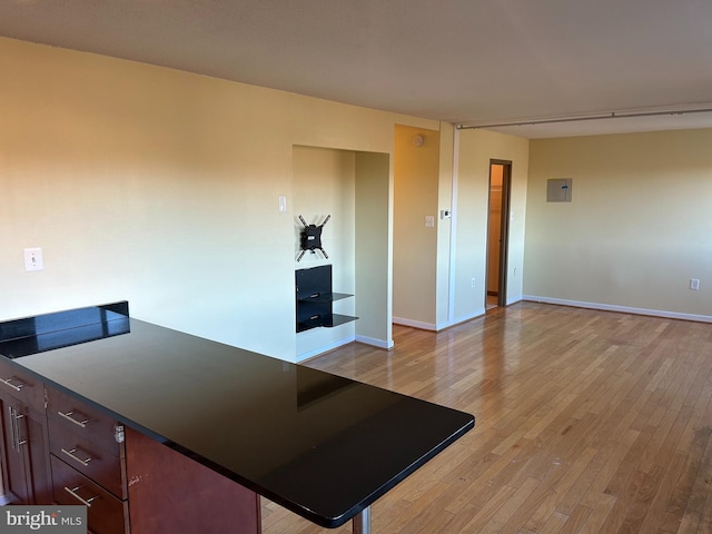 kitchen featuring a breakfast bar area, electric panel, and light hardwood / wood-style flooring