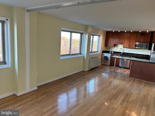 kitchen with sink, light hardwood / wood-style floors, washer / dryer, and stainless steel appliances