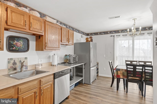 kitchen with sink, hanging light fixtures, light hardwood / wood-style flooring, a notable chandelier, and stainless steel appliances