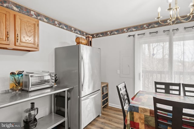 kitchen featuring electric panel, stainless steel fridge, light brown cabinetry, dark hardwood / wood-style flooring, and a chandelier