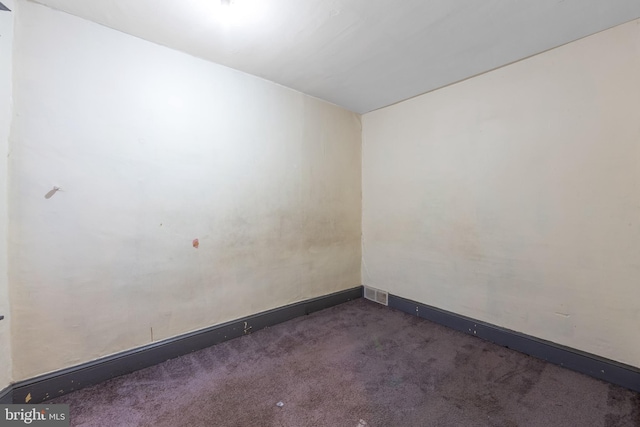 spare room with dark carpet