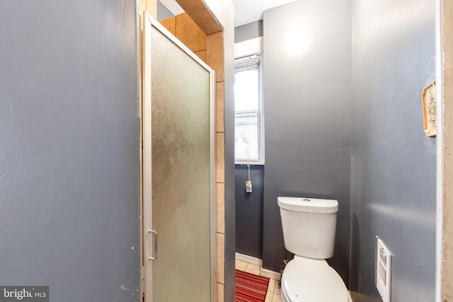 bathroom with toilet, tile patterned floors, and walk in shower