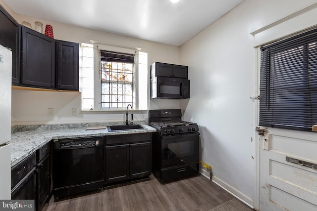 kitchen with black appliances, light stone counters, sink, and dark wood-type flooring