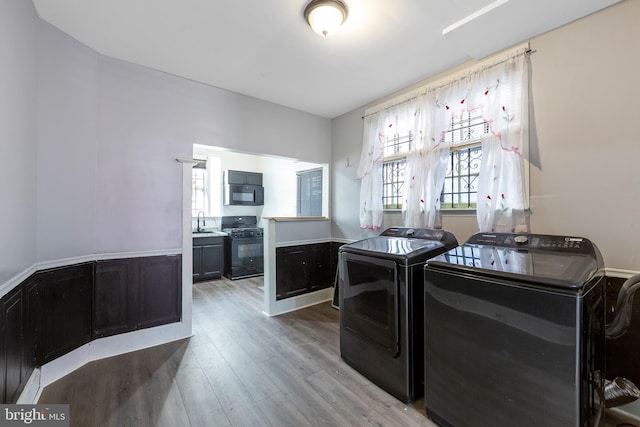 clothes washing area with separate washer and dryer, sink, and light hardwood / wood-style flooring