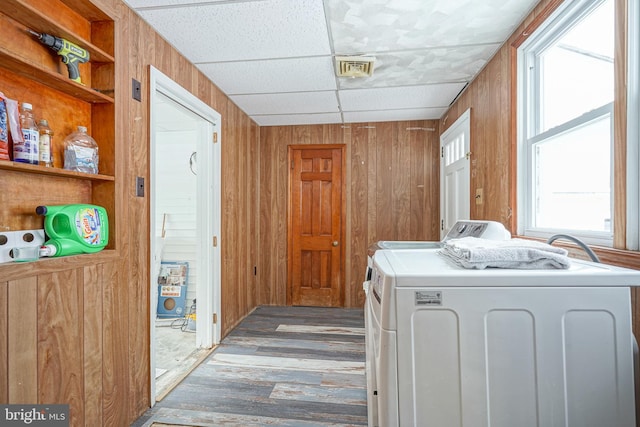 hallway with a paneled ceiling, built in shelves, hardwood / wood-style flooring, independent washer and dryer, and wood walls