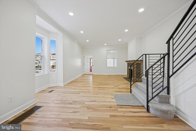 entrance foyer featuring ornamental molding and light hardwood / wood-style floors