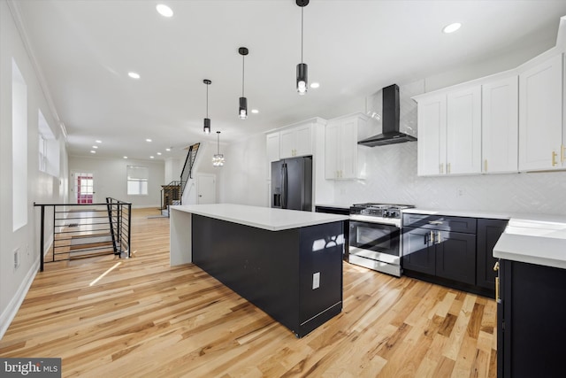 kitchen with decorative light fixtures, stainless steel gas stove, a center island, black refrigerator with ice dispenser, and wall chimney exhaust hood