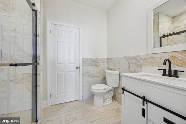 bathroom featuring walk in shower, vanity, toilet, and tile walls