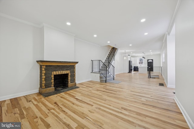 unfurnished living room with ornamental molding, a fireplace, and light hardwood / wood-style flooring