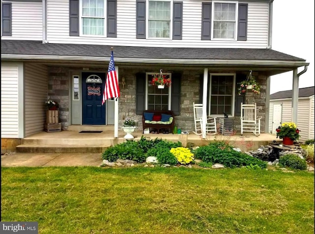 view of exterior entry featuring covered porch and a lawn